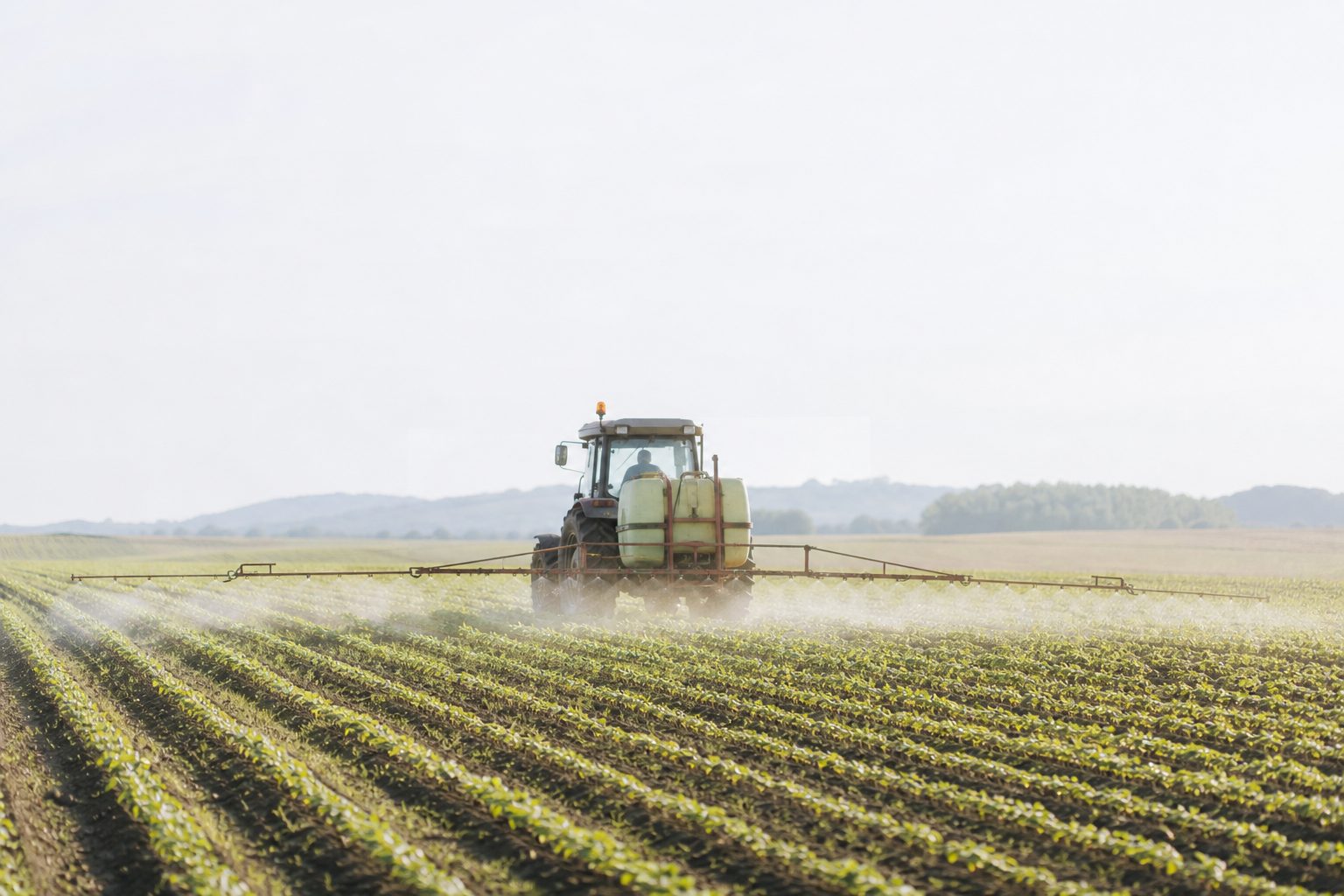 Trattore agricolo giallo fermo su un prato verde, con la cabina rivolta verso i campi.